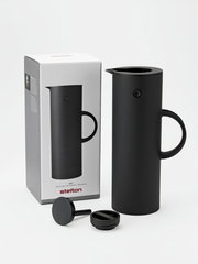 Schwarze Isolierkanne mit abgerundeter Form und Griff, abgebildet aus einer leicht seitlichen Perspektive neben ihrer Verpackung.