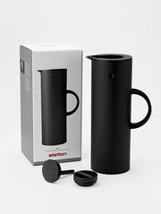 Schwarze Isolierkanne mit abgerundeter Form und Griff, abgebildet aus einer leicht seitlichen Perspektive neben ihrer Verpackung.