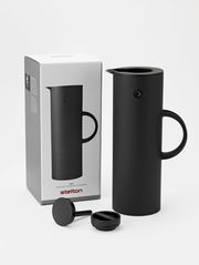 Schwarze Isolierkanne mit abgerundeter Form und Griff, abgebildet aus einer leicht seitlichen Perspektive neben ihrer Verpackung.