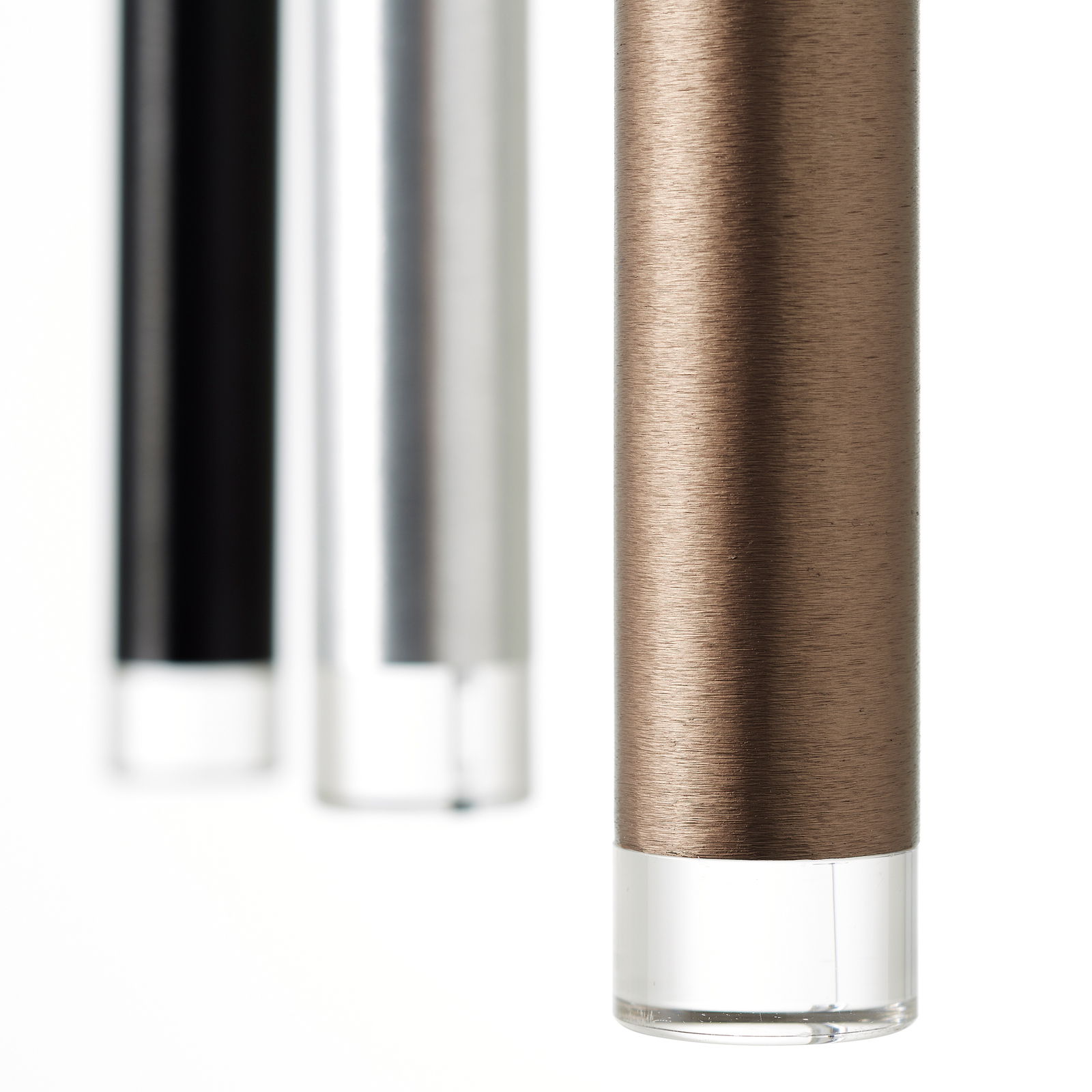 Nahaufnahme von drei zylindrischen LED-Leuchten in verschiedenen Farben: Schwarz, Silber und Bronze, mit klarem unteren Ende, aus seitlicher Perspektive.