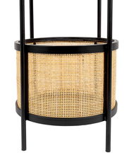 Nahaufnahme eines Beistelltisches mit schwarzem Metallrahmen und geflochtenem Rattan-Design.