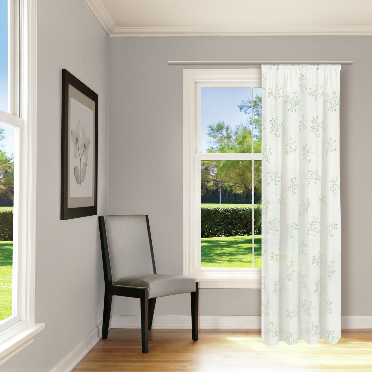 Heller Raum mit einem großen Fenster, durch das ein Vorhang mit grünem Blattmuster hängt. Ein grauer Stuhl steht in der Ecke. Perspektive von innen nach außen.