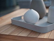 Graues Tablett mit abgerundeten Ecken, auf einem Holztisch stehend, mit drei dekorativen Vasen. Perspektive von schräg oben.