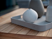 Graues Tablett mit abgerundeten Ecken, auf einem Holztisch stehend, mit drei dekorativen Vasen. Perspektive von schräg oben.