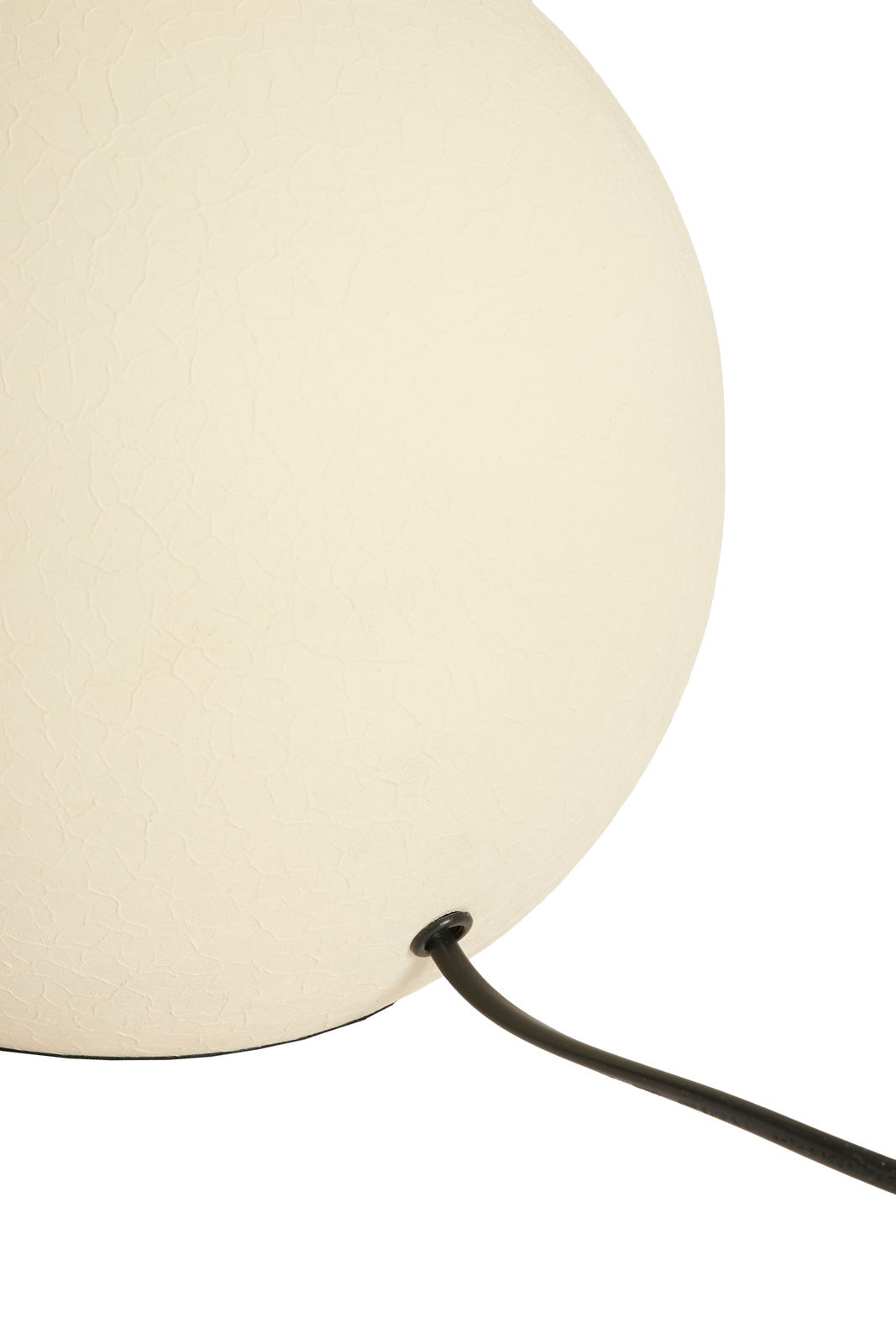 Nahaufnahme eines weißen Lampenfußes mit Textur und schwarzem Kabel, seitliche Perspektive