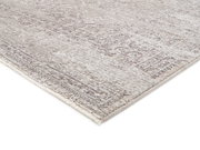 Nahaufnahme eines Designer-Teppichs mit subtilen Mustern in Grau- und Beigetönen, perspektivisch von der Seite aufgenommen.