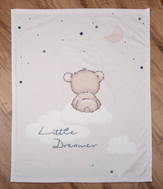 Weiche Decke mit einem niedlichen Bärenmotiv, der auf einer Wolke sitzt, umgeben von Sternen und dem Mond. Perspektive von oben.