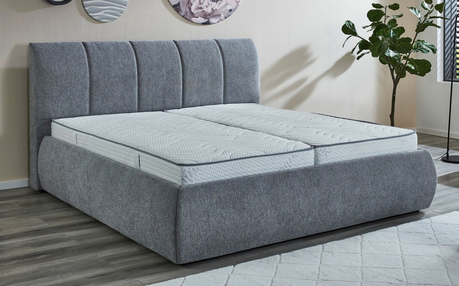 Graues Polsterbettgestell mit hohem Kopfteil, seitlicher Blickwinkel