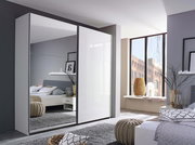 Moderner Schwebetürenschrank mit zwei Türen, eine davon mit Spiegel, in einem stilvoll eingerichteten Schlafzimmer. Perspektive von schräg vorne.