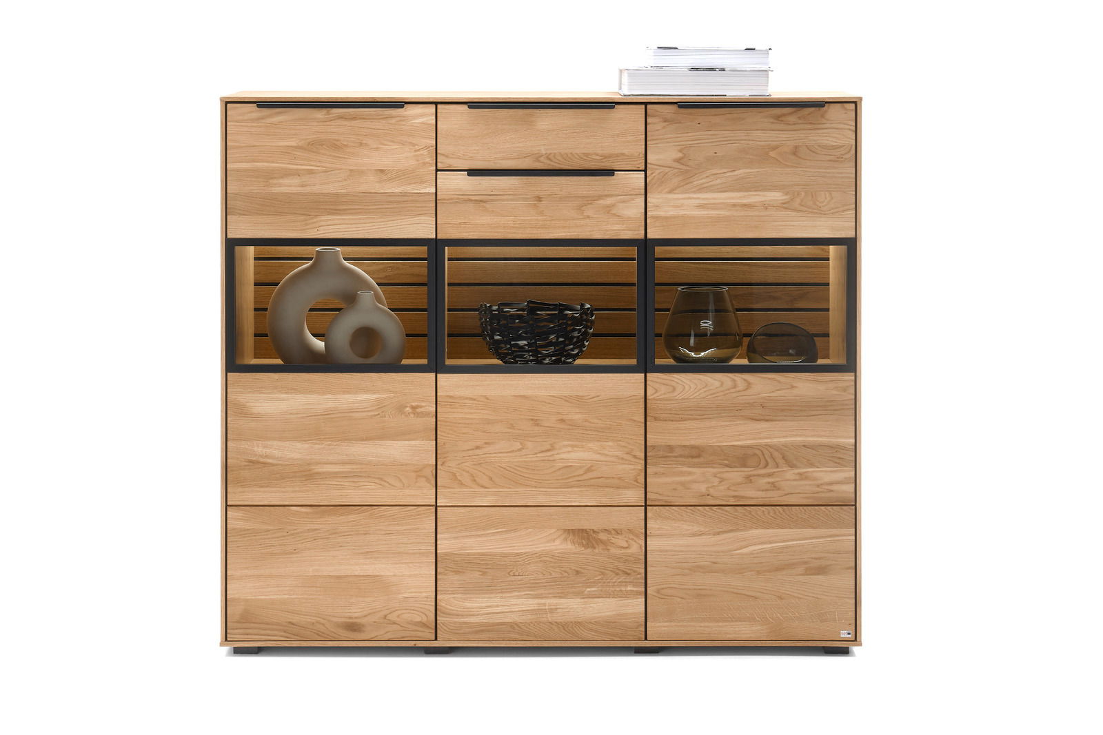 Set one by Musterring Highboard SET ONE JACKSON Frontale Ansicht eines modernen Highboards aus Holz mit Glasvitrinen und dekorativen Objekten.