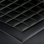 Nahaufnahme der schwarzen Polsterung eines Gaming-Stuhls mit grünen Nähten in Rautenmuster, Draufsicht.