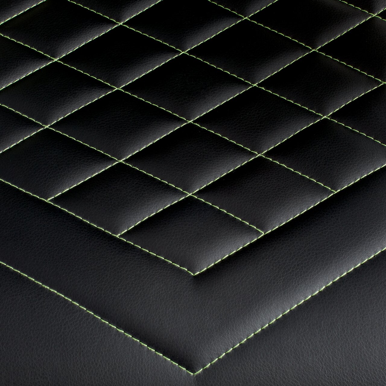 Close-up van de zwarte bekleding van een gamingstoel met groene stiksels in ruitpatroon, gezien van bovenaf.