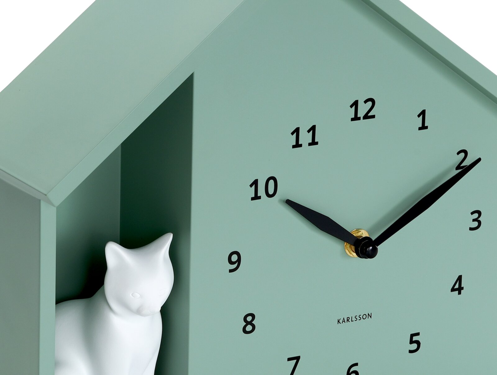 Grüne Wanduhr mit schwarzem Zifferblatt und Zeigern, dekoriert mit einer weißen Katzenfigur in einem seitlichen Fach, seitliche Perspektive.