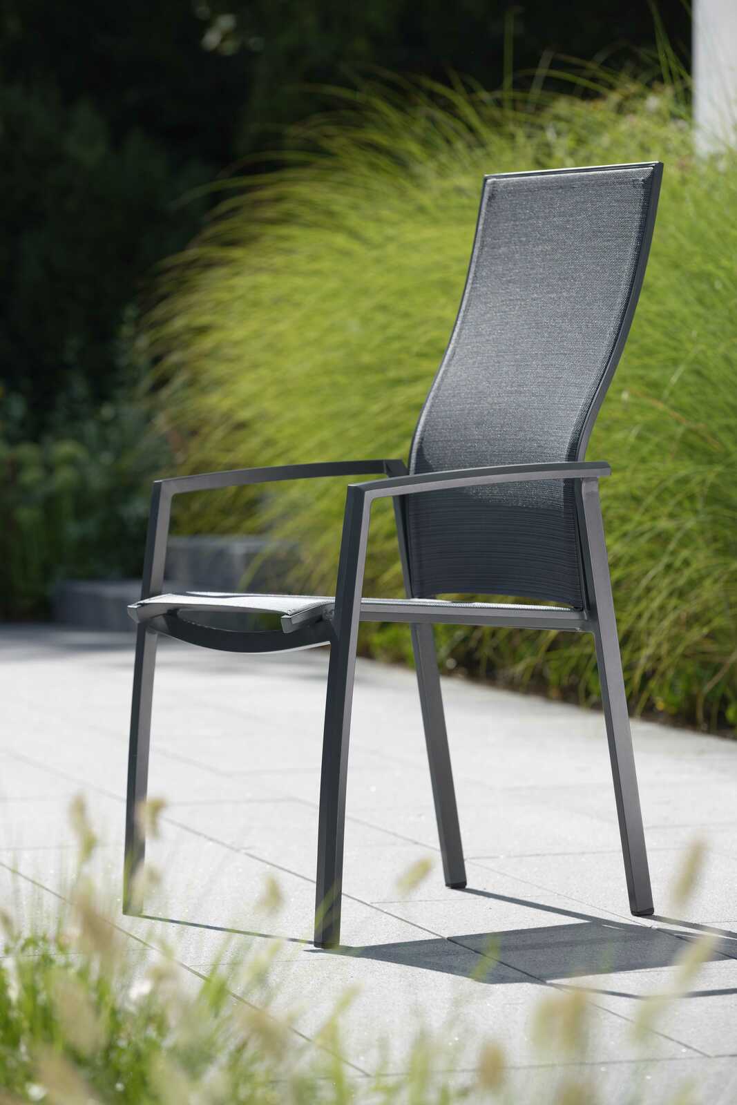 Stern Stapelsessel KARI Moderner Stapelsessel KARI aus Metall mit hoher Rückenlehne, seitliche Perspektive, im Freien auf einer Terrasse platziert.