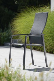 Moderner Stapelsessel KARI aus Metall mit hoher Rückenlehne, seitliche Perspektive, im Freien auf einer Terrasse platziert.