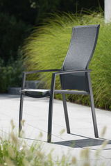Moderner Stapelsessel KARI aus Metall mit hoher Rückenlehne, seitliche Perspektive, im Freien auf einer Terrasse platziert.