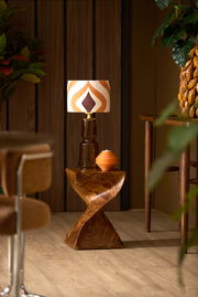 Retro-Lampenschirm mit geometrischem Muster in warmen Farben, auf einem Holztisch in einem stilvollen Raum, seitliche Perspektive.