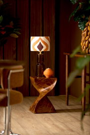 Retro lampenkap met geometrisch patroon in warme kleuren, op een houten tafel in een stijlvolle ruimte, zijaanzicht.