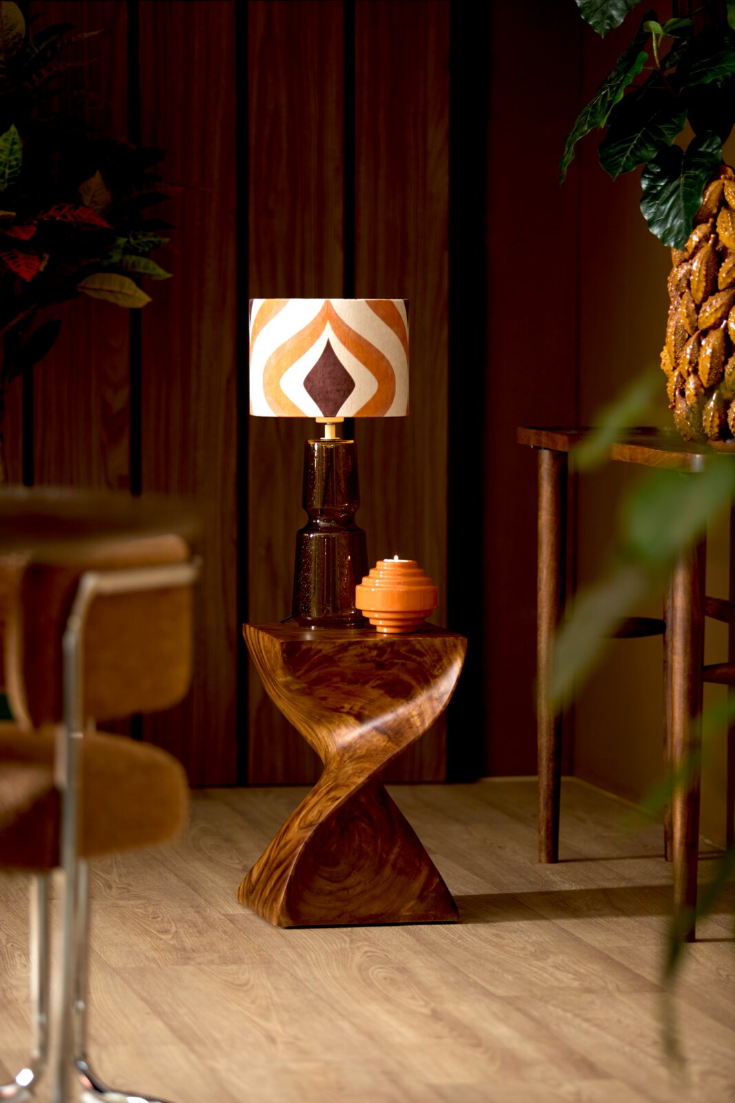 Retro lampenkap met geometrisch patroon in warme kleuren, op een houten tafel in een stijlvolle ruimte, zijaanzicht.
