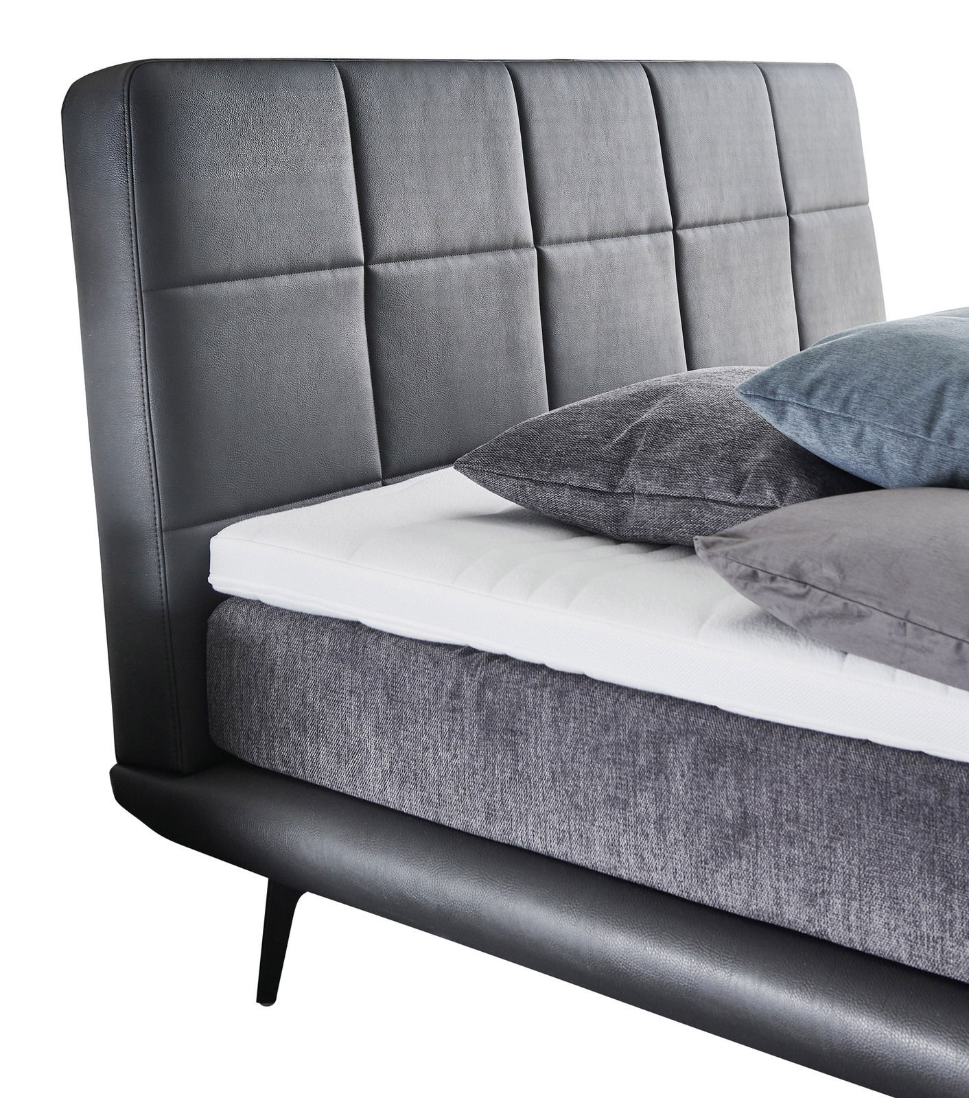 Boxspringbett mit grauem Kopfteil und Kissen, seitliche Perspektive