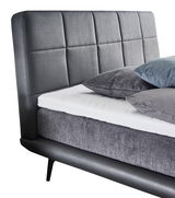 Boxspringbett mit grauem Kopfteil und Kissen, seitliche Perspektive
