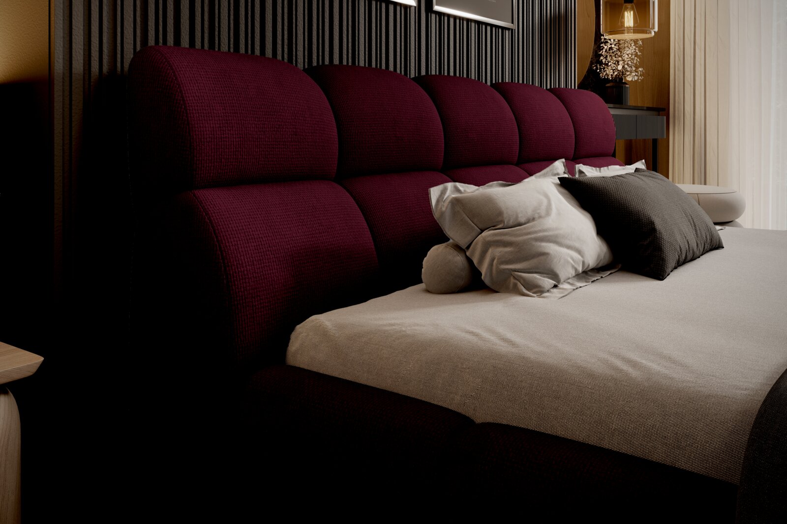 Zijaanzicht van een elegant gestoffeerd bed met een wijnrood hoofdeinde en diverse kussens in een stijlvol ingerichte slaapkamer.
