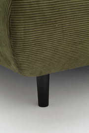 Nahaufnahme eines grünen, gerippten Sofas mit schwarzem Bein, seitliche Perspektive.