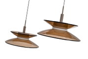 Twee moderne hanglampen met dubbele, amberkleurige glazen kappen en zwarte snoeren, schuin van onderen gezien tegen een witte achtergrond