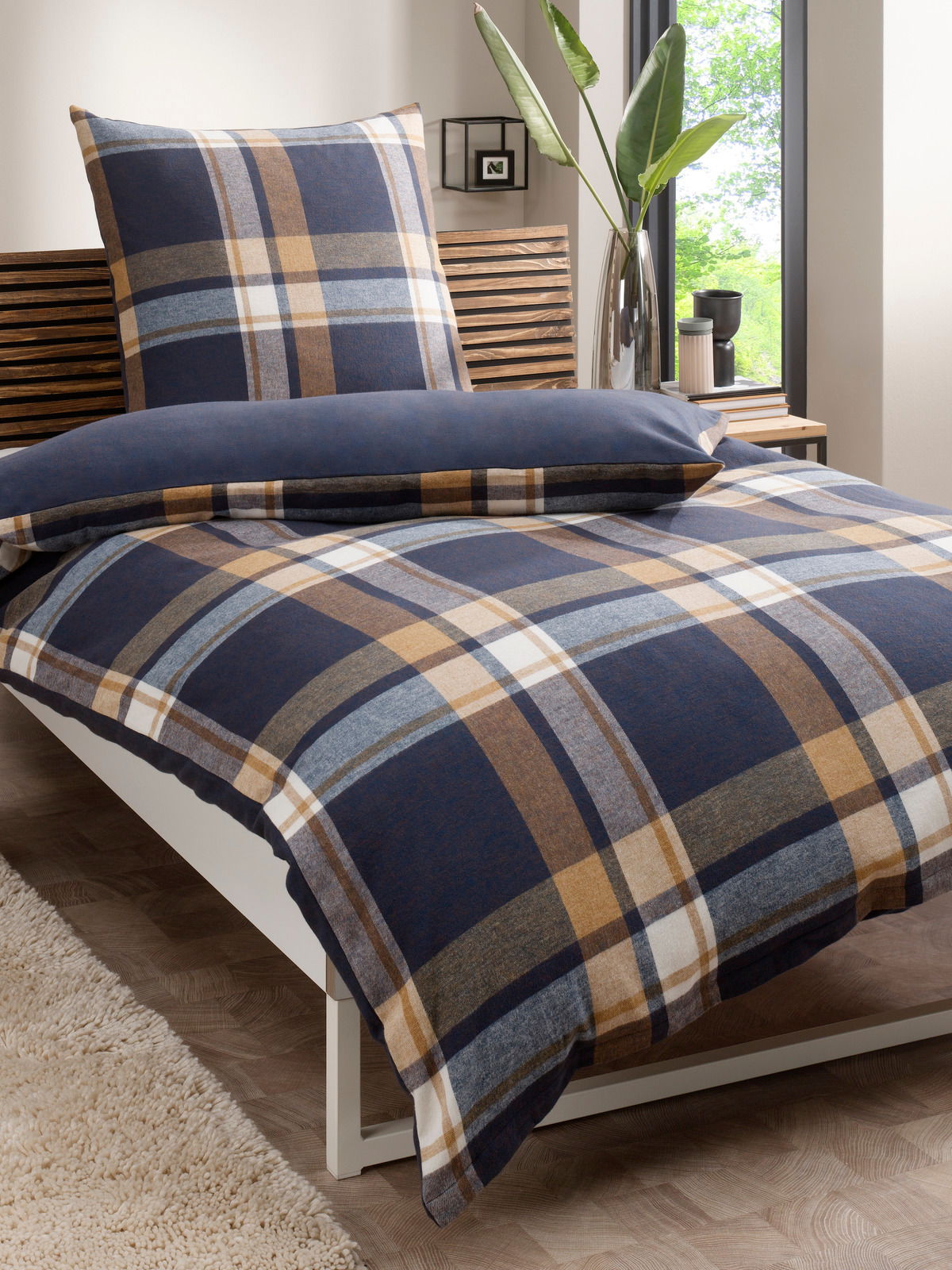 Wendebettwäsche 135x200cm mit kariertem Muster in Blau- und Brauntönen, auf einem Bett in einem modernen Schlafzimmer mit Pflanzen im Hintergrund, seitliche Perspektive