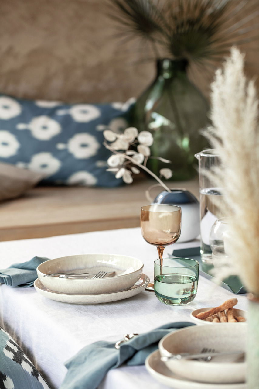 Ein stilvoll gedeckter Tisch mit einem Weinkelch aus einem 2-teiligen Set, in einer gemütlichen und eleganten Atmosphäre. Perspektive: seitlich.