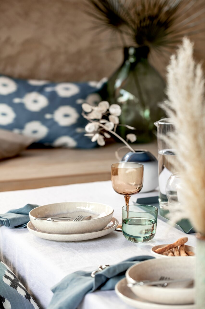 Ein stilvoll gedeckter Tisch mit einem Weinkelch aus einem 2-teiligen Set, in einer gemütlichen und eleganten Atmosphäre. Perspektive: seitlich.