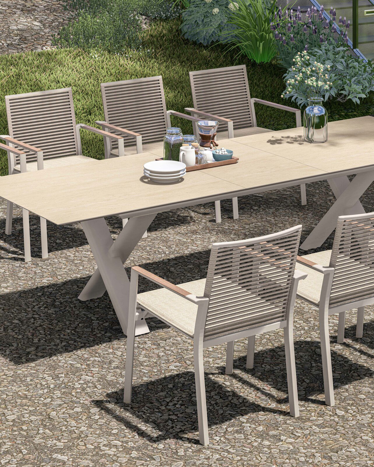 Garten Ausziehtisch mit sechs Stühlen, gedeckt mit Geschirr und Blumen, aus seitlicher Perspektive fotografiert.