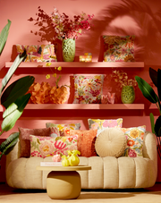 Gemütliche Couch mit bunten Kissen und dekorativen Vasen, frontal fotografiert.