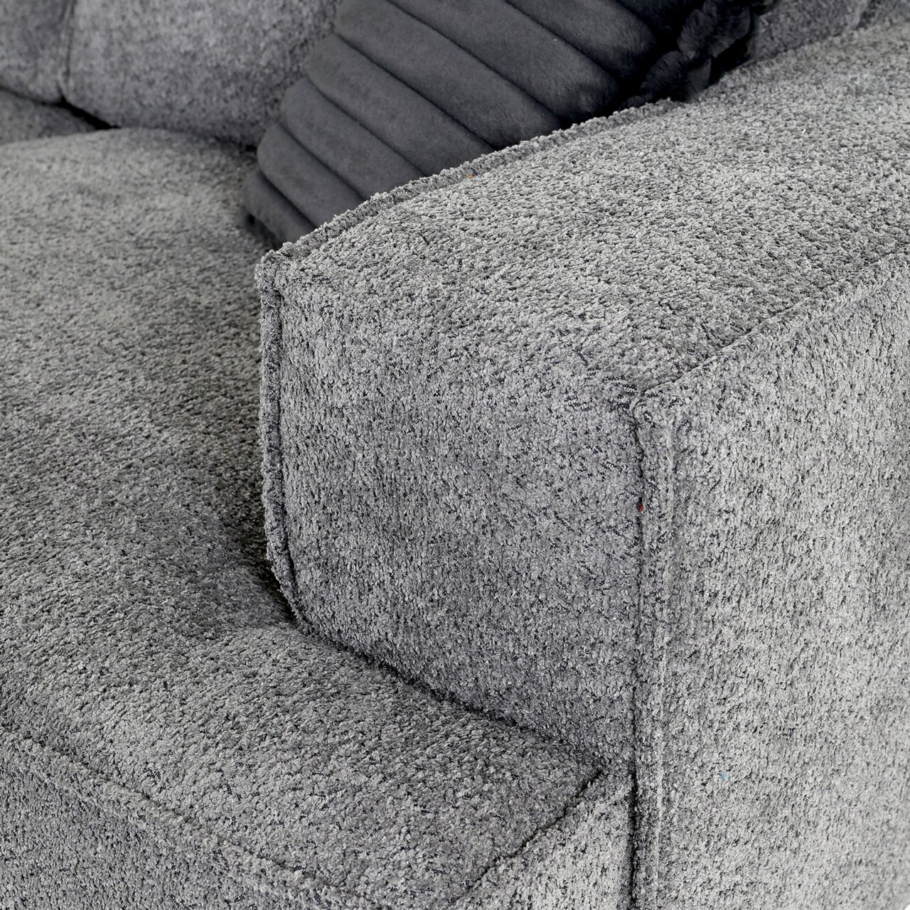 Graues Ecksofa mit strukturierter Oberfläche, Nahaufnahme der Armlehne von der Seite.