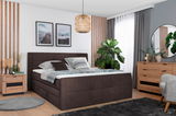 Boxspringbett 180 in einem modernen Schlafzimmer, seitliche Perspektive, mit Holzmöbeln und Pflanzen dekoriert.