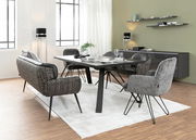 Moderner Esstisch mit schwarzer Tischplatte und Metallbeinen, umgeben von stilvollen Stühlen in einem hellen, eleganten Esszimmer. Perspektive von der Seite.