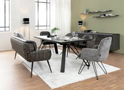 Moderner Esstisch mit schwarzer Tischplatte und Metallbeinen, umgeben von stilvollen Stühlen in einem hellen, eleganten Esszimmer. Perspektive von der Seite.