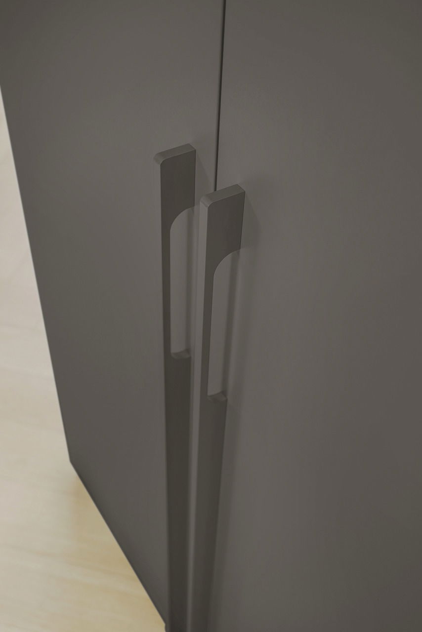 Nahaufnahme der Griffe eines grauen Drehtürenschranks aus der Vogelperspektive.