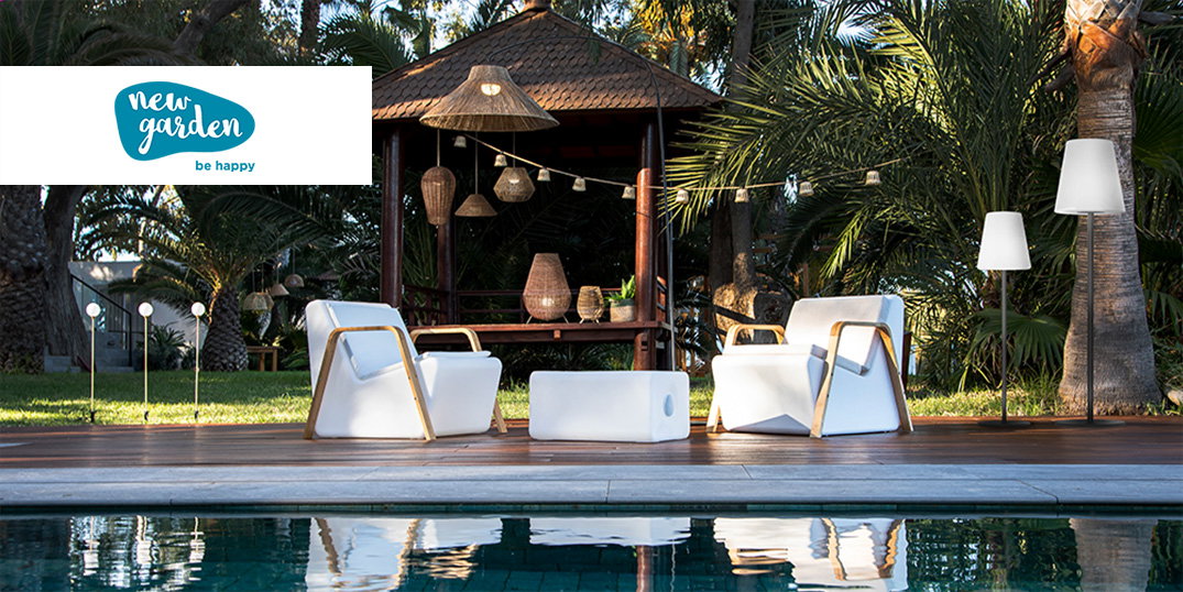 Een elegante buitenlounge, omringd door tropisch groen en met witte meubels van het merk New Garden.