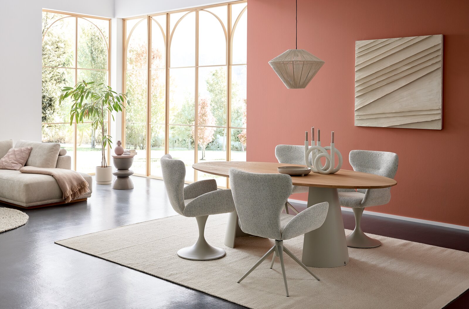 Musterring Armlehnstuhl MR JUSTB! Moderner Essbereich mit ovalem Esstisch und vier gepolsterten Armlehnstühlen in einem hellen Raum mit großen Fenstern. Perspektive von der Seite.