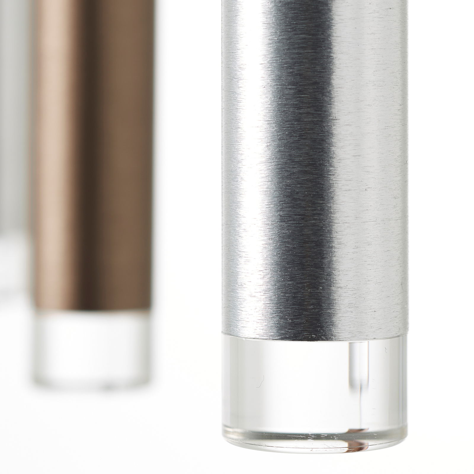 Nahaufnahme von zylindrischen Metall-LED-Leuchten mit gebürsteter Oberfläche und transparentem Ende, perspektivisch von der Seite betrachtet.