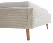 Close-up van een gestoffeerd bed met een beige, geribbelde stoffen bekleding en houten poten, gezien vanaf de zijkant