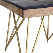 Nahaufnahme eines Beistelltisches mit schwarzer Holzplatte und goldenen Metallbeinen in geometrischem Design, seitliche Perspektive