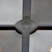 Detailansicht einer modernen Deckenleuchte aus der Untersicht mit gebürstetem Metallkreuz, rundem Zentrum und vier satinierten Glasflächen