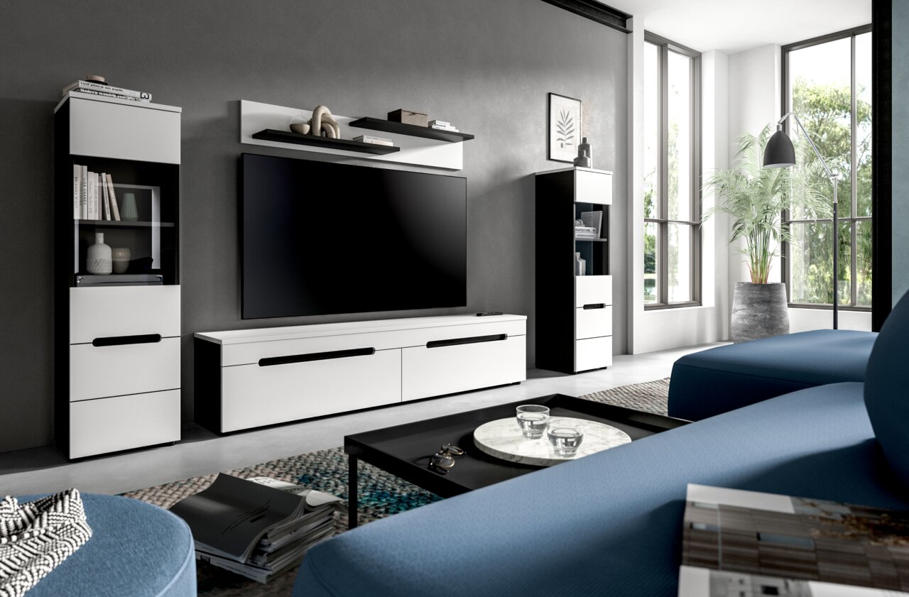MID.YOU Wohnkombination CANU Modernes Wohnzimmer mit weiß-schwarzer TV-Wand (Lowboard, zwei Vitrinenschränke und Wandregal) und großem Flachbildfernseher, fotografiert in frontaler Perspektive leicht von rechts.