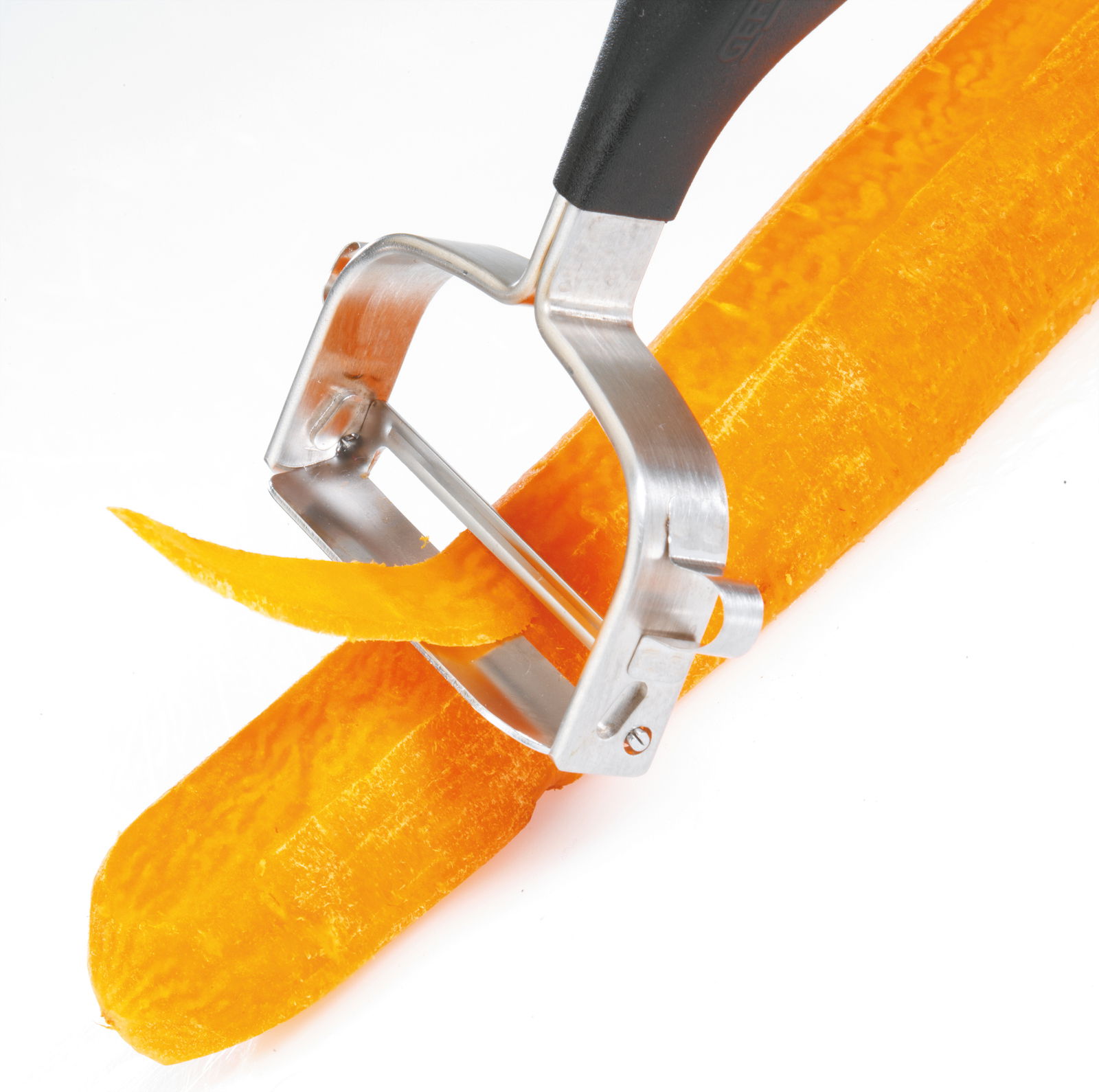 Nahaufnahme eines Sparschälers 'Universale', der eine Karotte schält, mit Fokus auf die Klinge und den Schälvorgang.