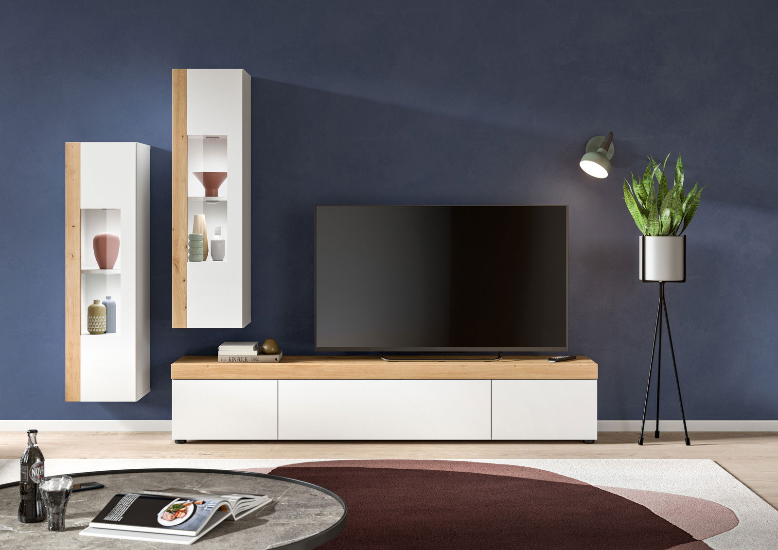 Moderne Wohnzimmer-Vitrine in Weiß und Holzoptik, frontal betrachtet, mit dekorativen Objekten und einem großen Fernseher.