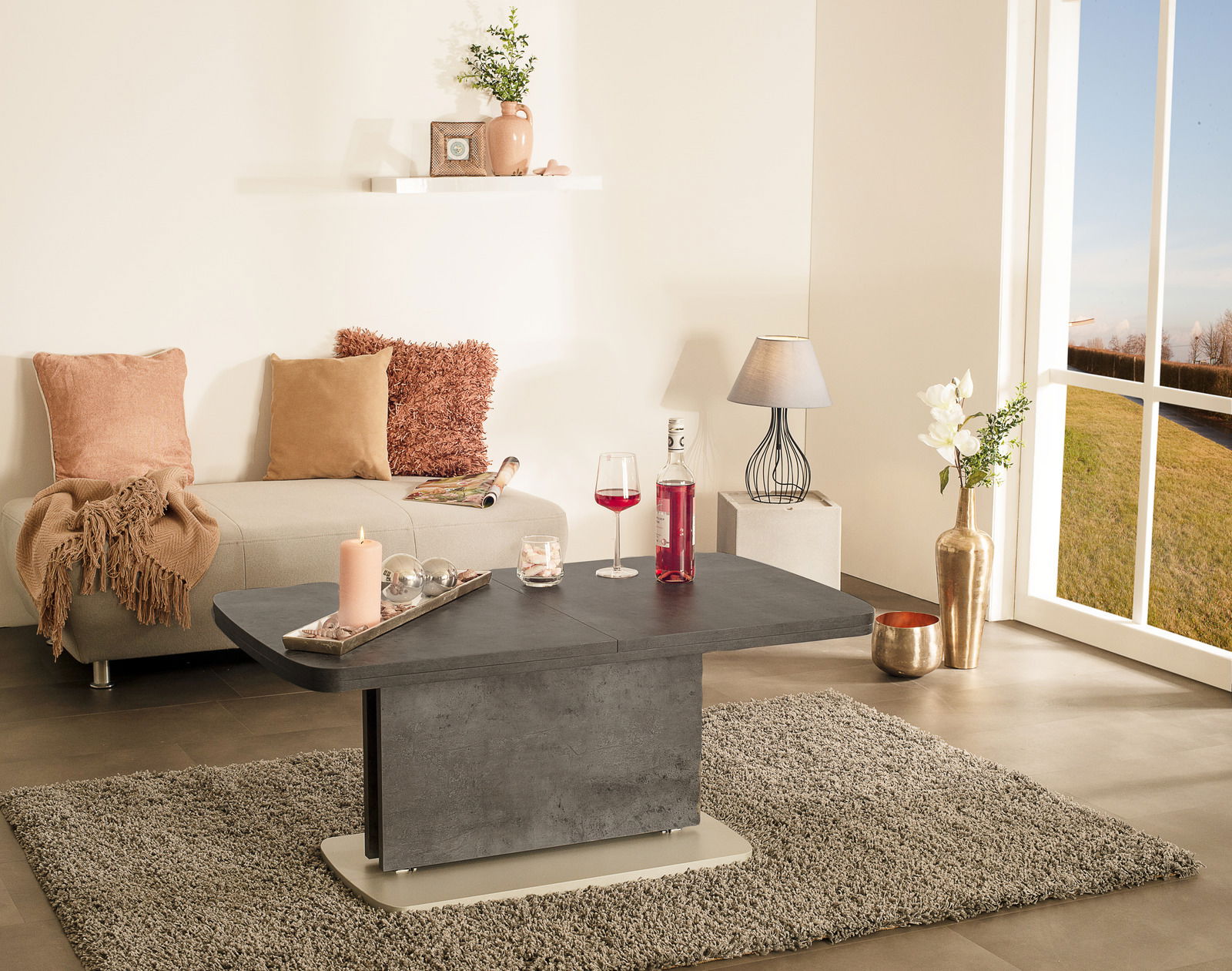 Moderner Couchtisch in Betonoptik, zentral im Wohnzimmer platziert, umgeben von stilvoller Dekoration und einem großen Fenster mit Blick ins Freie.