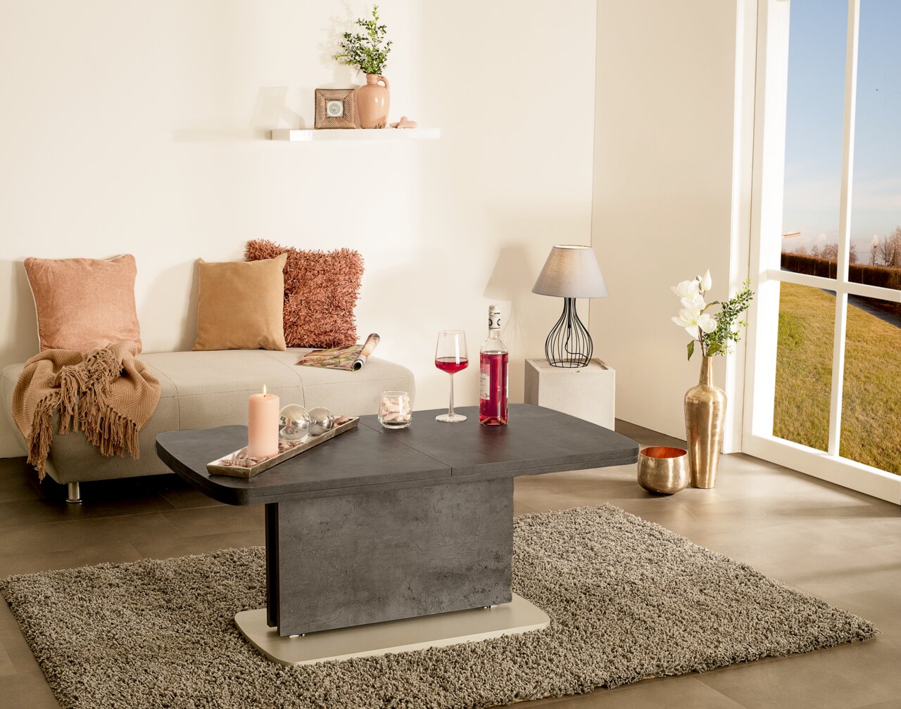 Zurbrüggen Salontafel JAMAIKA I Moderne salontafel in betonlook, centraal in de woonkamer geplaatst, omringd door stijlvolle decoratie en een groot raam met uitzicht naar buiten.