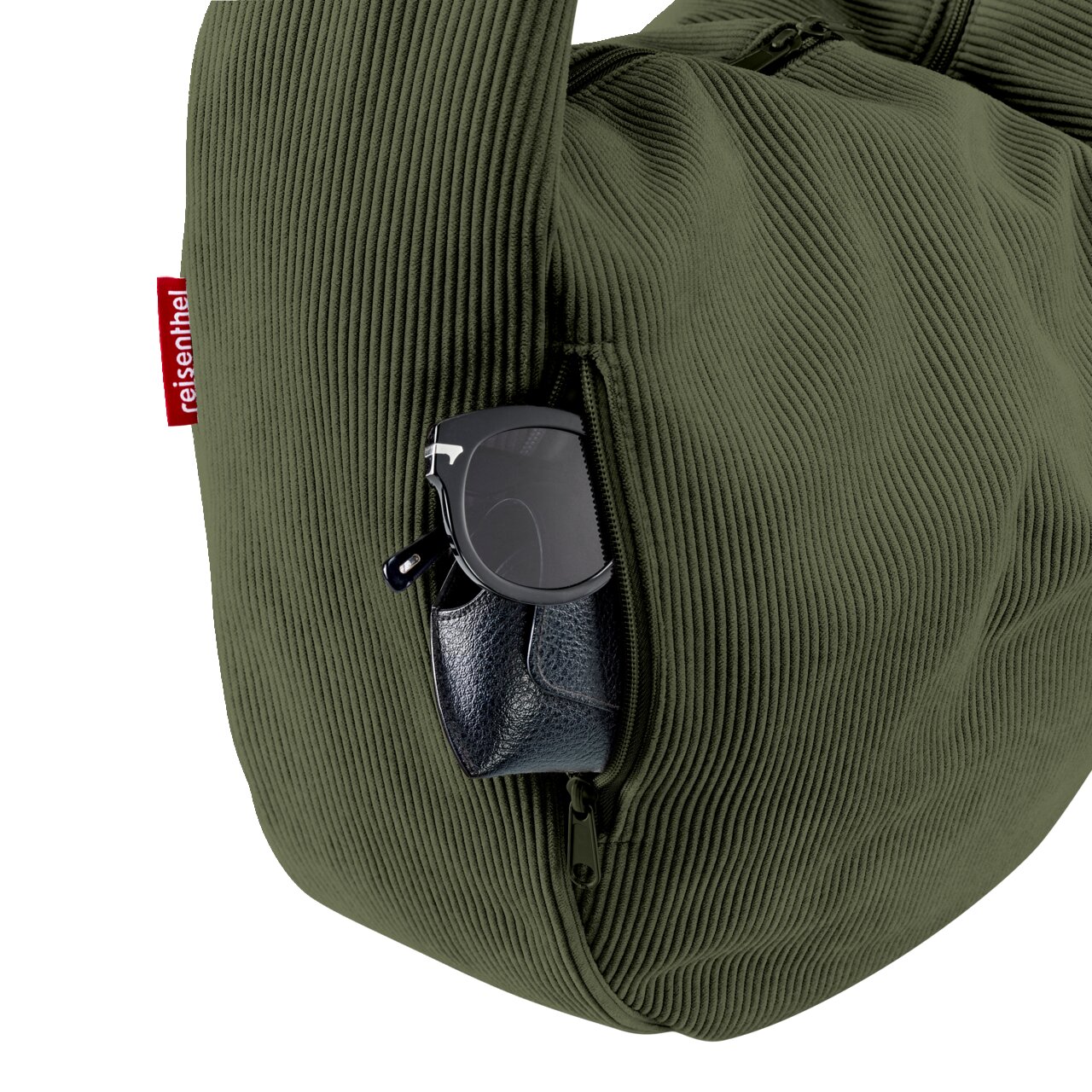 Olivegrüne Reisenthel-Tasche aus Cord mit seitlichem Reißverschlussfach, darin Sonnenbrille und Etui; Detailaufnahme aus seitlicher Perspektive